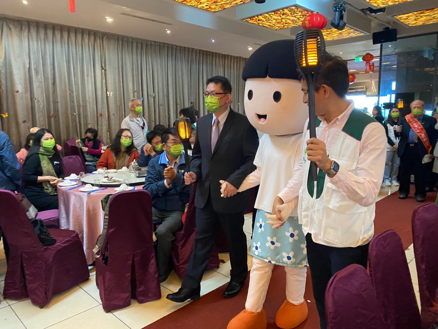 由家扶基金會執行長周大堯(左)、中心主任施政延(右),以及家扶WaWa手持火把進場。