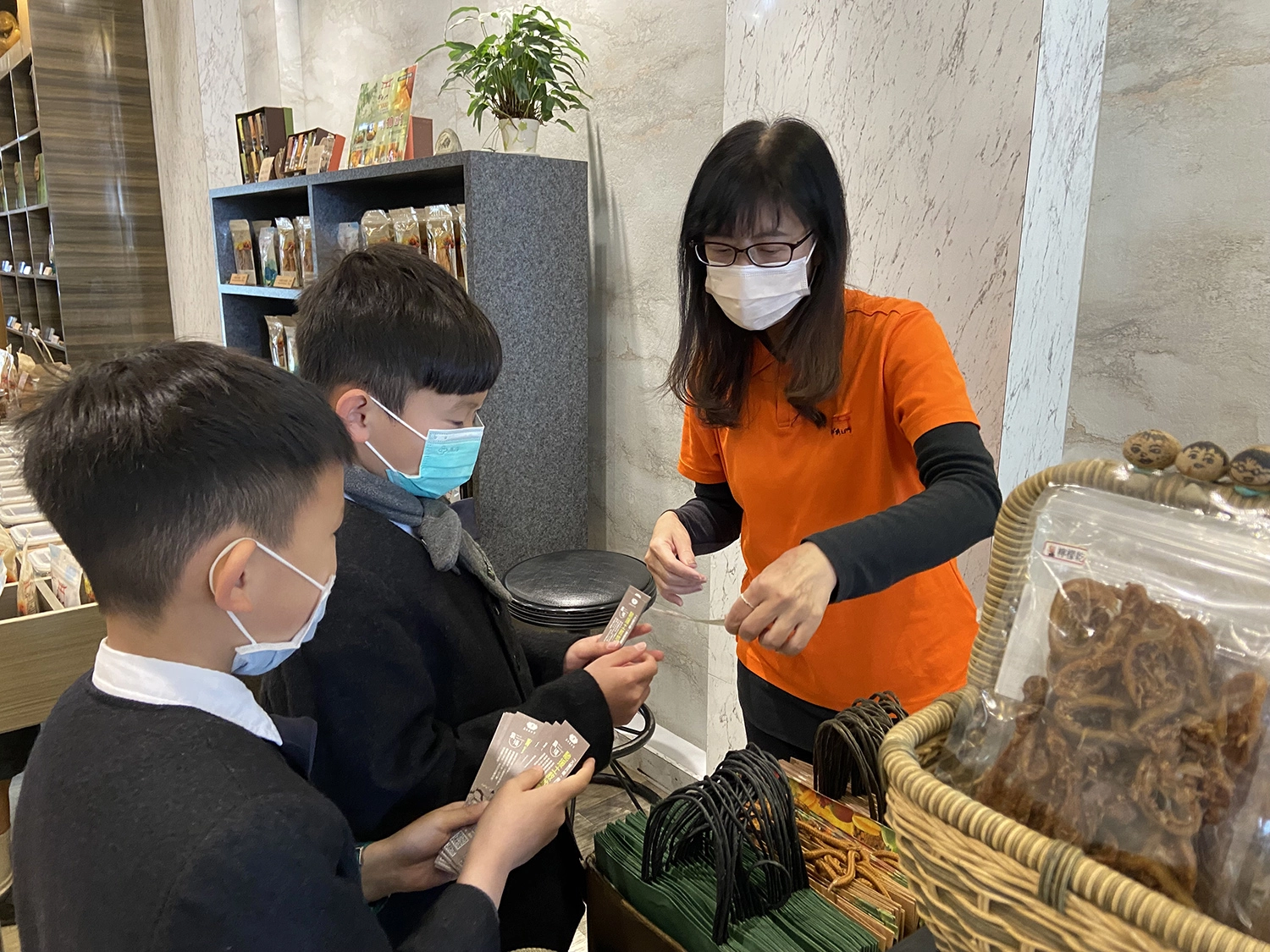 彬彬有禮的國小吳宥澄(圖中)及周信叡(圖左)向店家說明土敘地震援助的訊息。(林昱汝攝影)