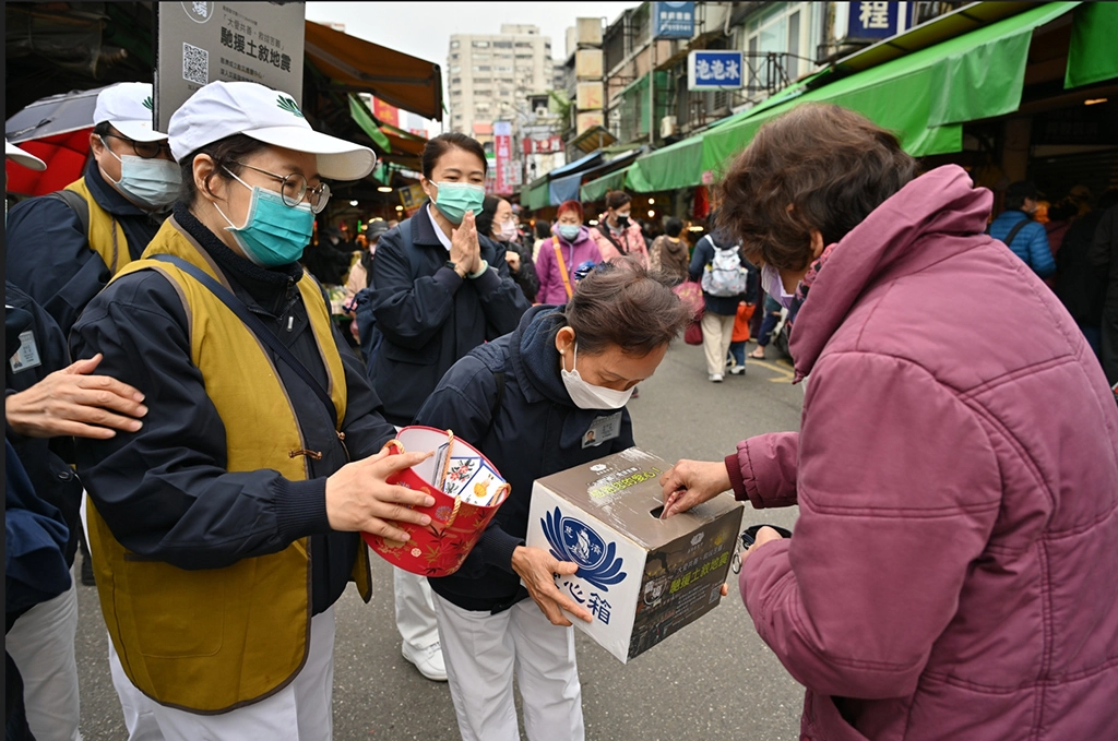 人潮熱鬧的南京東路五段二九一巷菜市場,像是拜訪老朋友似的,經過許多菜販、水果攤、等貨攤志工打招呼募心也募款。