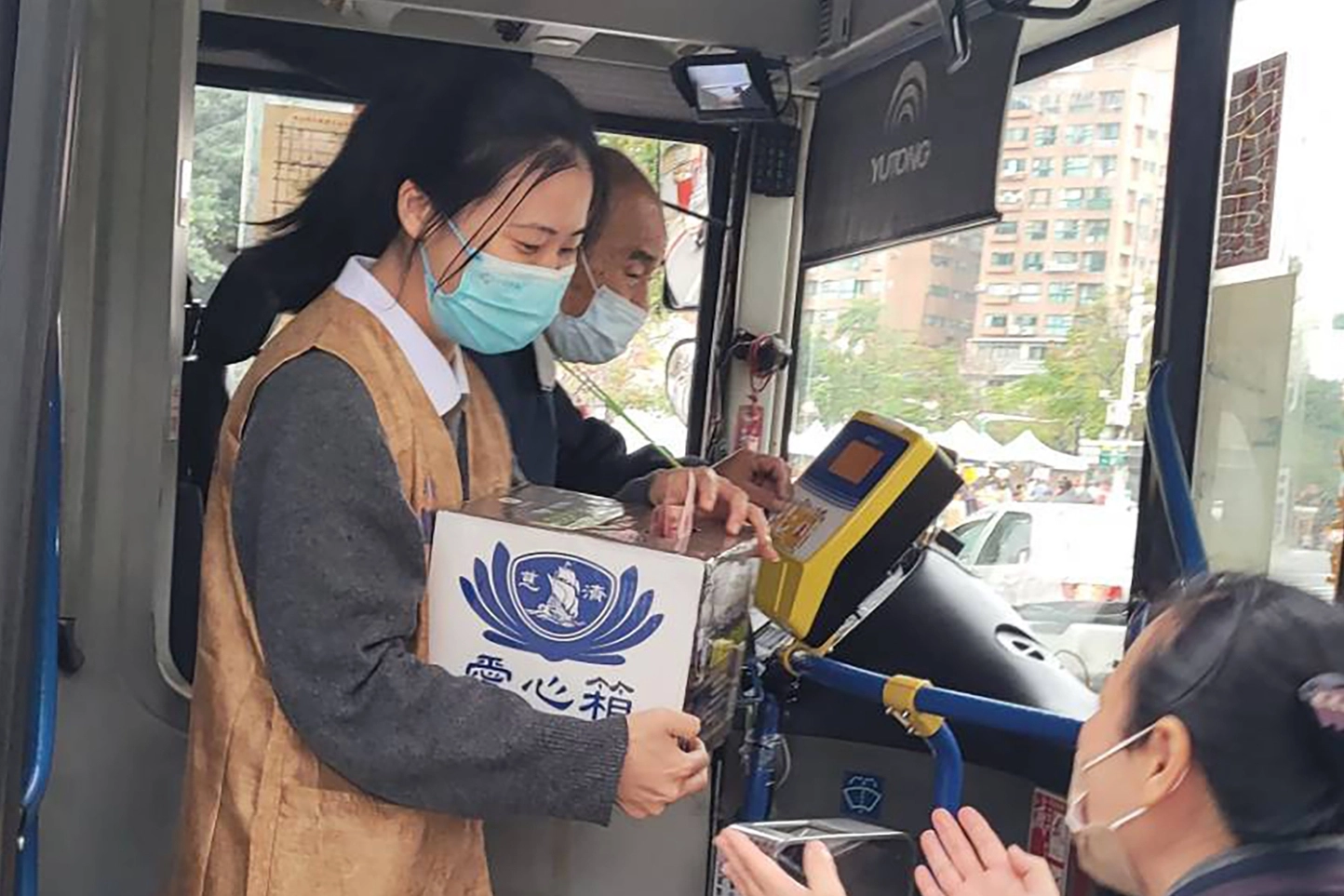 乘客下車後停等紅綠燈的公車司機,請志工抱愛心箱上公車讓他為土耳其盡一點心力。