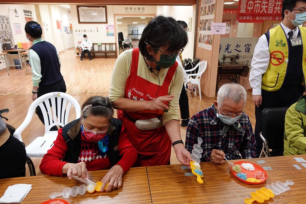 園藝治療師洪榛騏老師(中)指導長輩動手做五行飯糰。