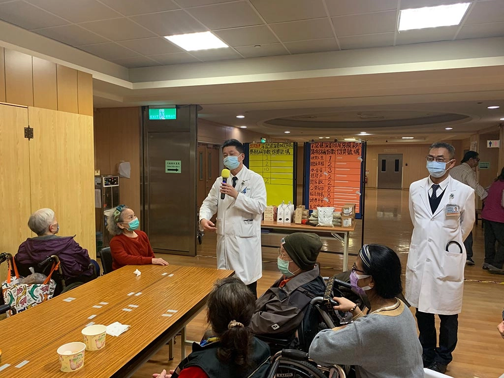 社區健康中心主任陳慶元(左)、神經內科醫師傅進華(右)來與長輩摸彩、切蛋糕同歡。