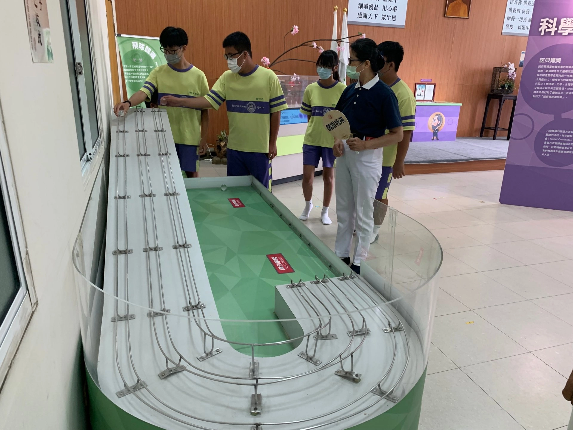 力學實驗室的「飛球競速」展區,林鎮宇(左一)從中體會,下坡路段坡道太斜,轉彎弧度過大,開車或騎機車、腳踏車如果沒有減速,車子可能會翻車或直接甩出去而受傷。