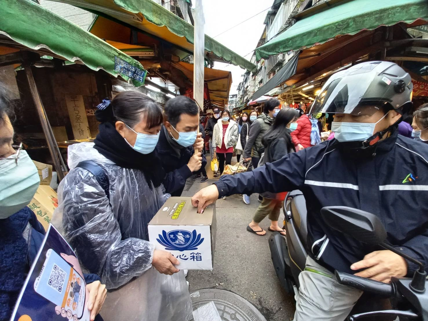 志工走入街頭向社會大眾募心募愛。雙手捧著募款箱和宣導舉牌,在汐止橫科力行市場,往來民眾都紛紛投下愛心馳援。