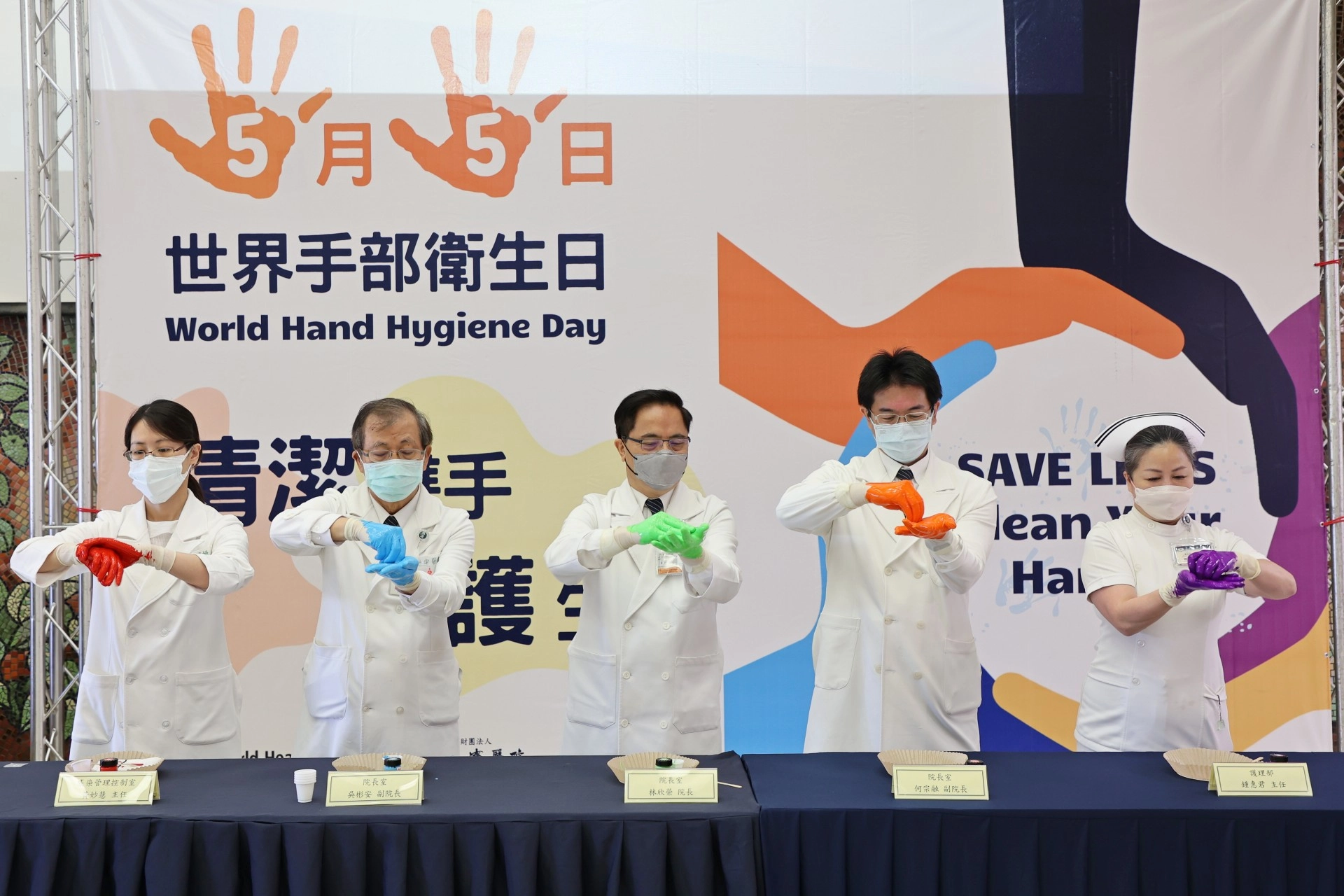 左起感控室主任黃妙慧、副院長吳彬安、院長林欣榮、副院長何宗融、護理部主任鍾惠君,以顏料示範正確洗手7步驟(內、外、夾、弓、大、立、腕)。