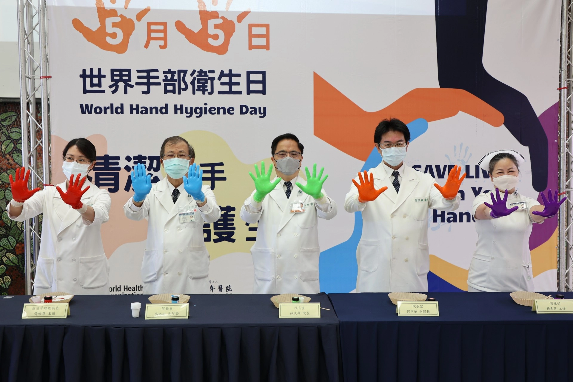左起感控室主任黃妙慧、副院長吳彬安、院長林欣榮、副院長何宗融、護理部主任鍾惠君,以顏料示範正確洗手7步驟(內、外、夾、弓、大、立、腕)。
