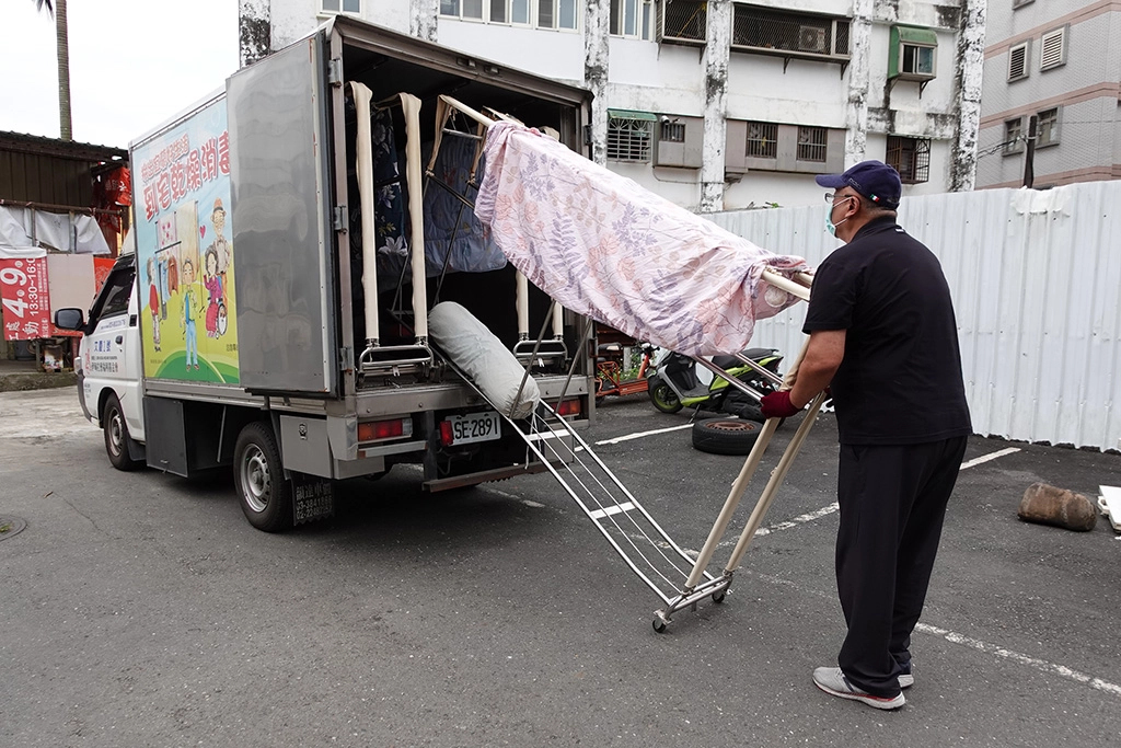 伊甸宜蘭乾燥消毒車操作人員將案家的被單與衣服上架,進行除濕、消毒與烘乾等清潔工作。