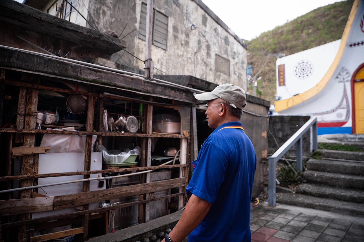 住在椰油部落的阿佳,家外牆被解體剝落,從室外就能看見家中馬桶和廚房。圖為阿佳爸爸檢視遭颱風破壞的房屋 (台灣世界展望會提供)