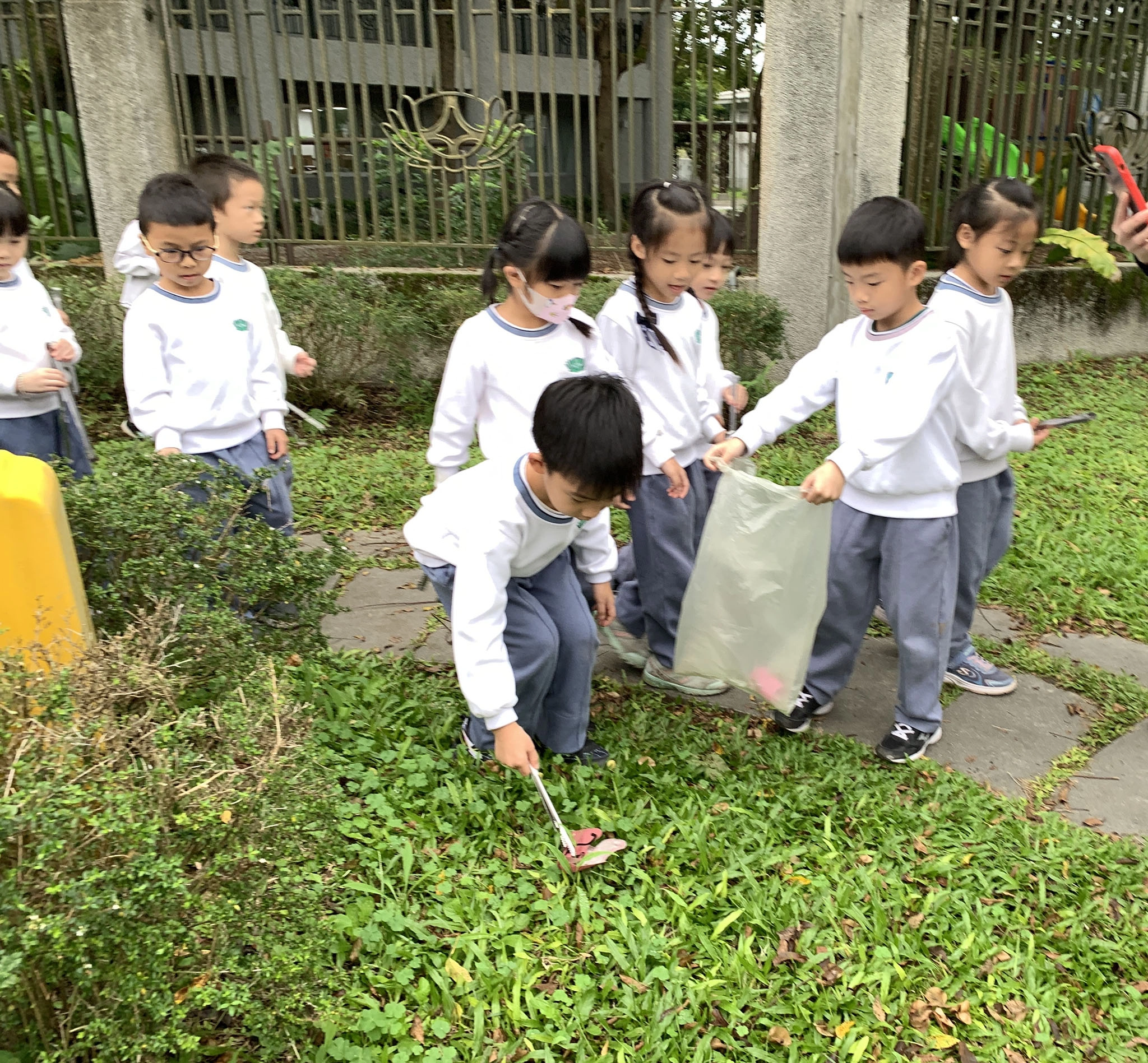 幼兒園相互合作，草叢中小紙屑也不放過