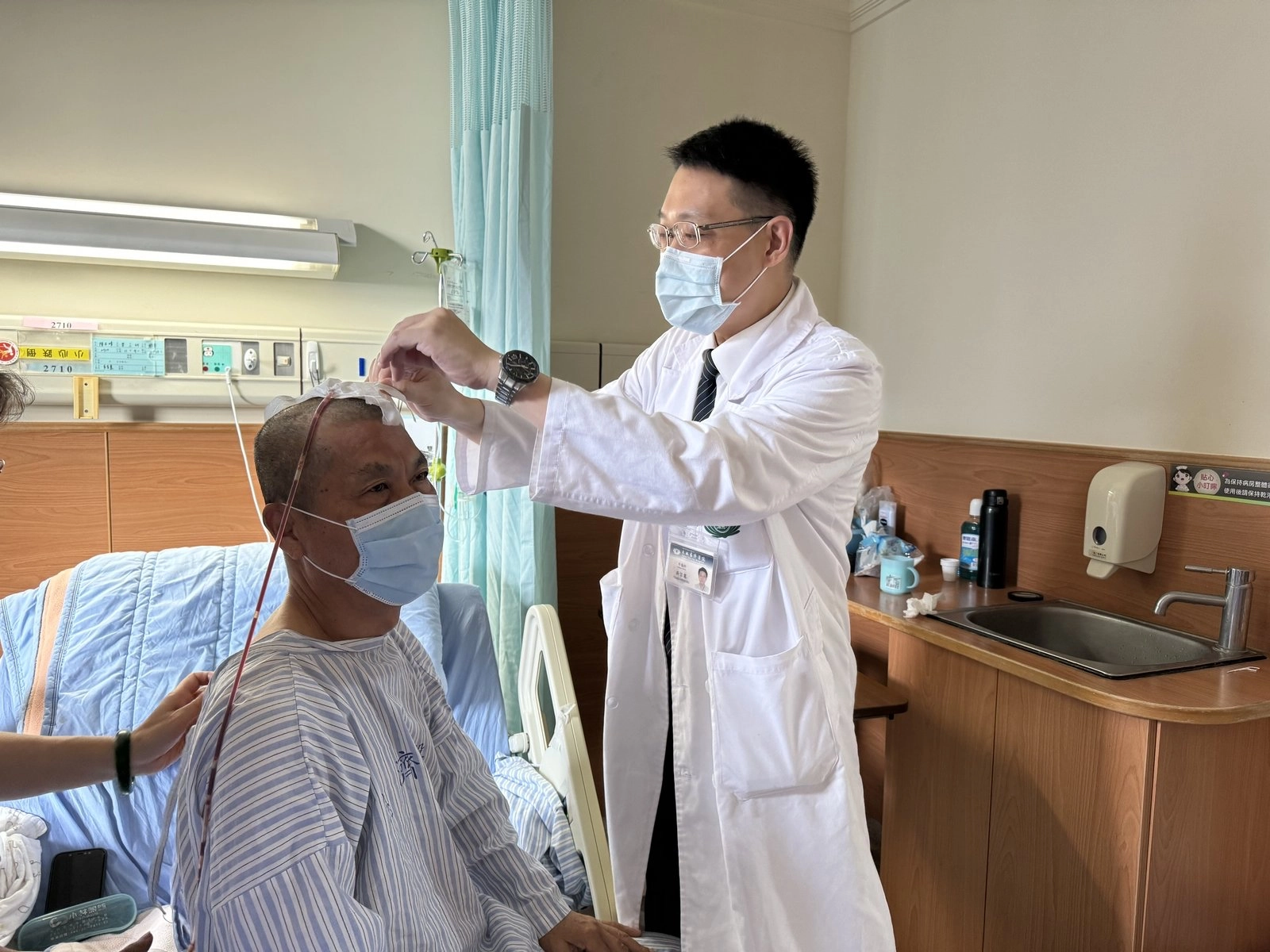 神經外科吳宗憲醫師為陳先生手術治療後,查看置入引流管狀況