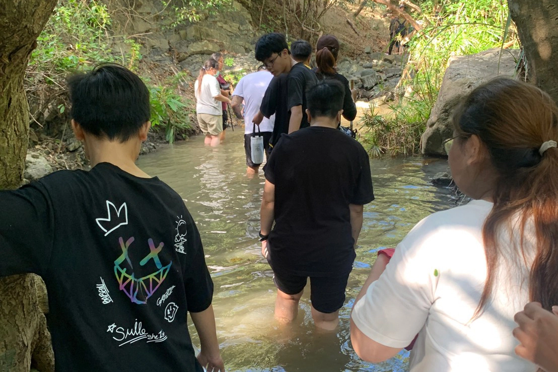 孩子不時回頭確認媽媽涉水狀況，提醒水底有石頭。