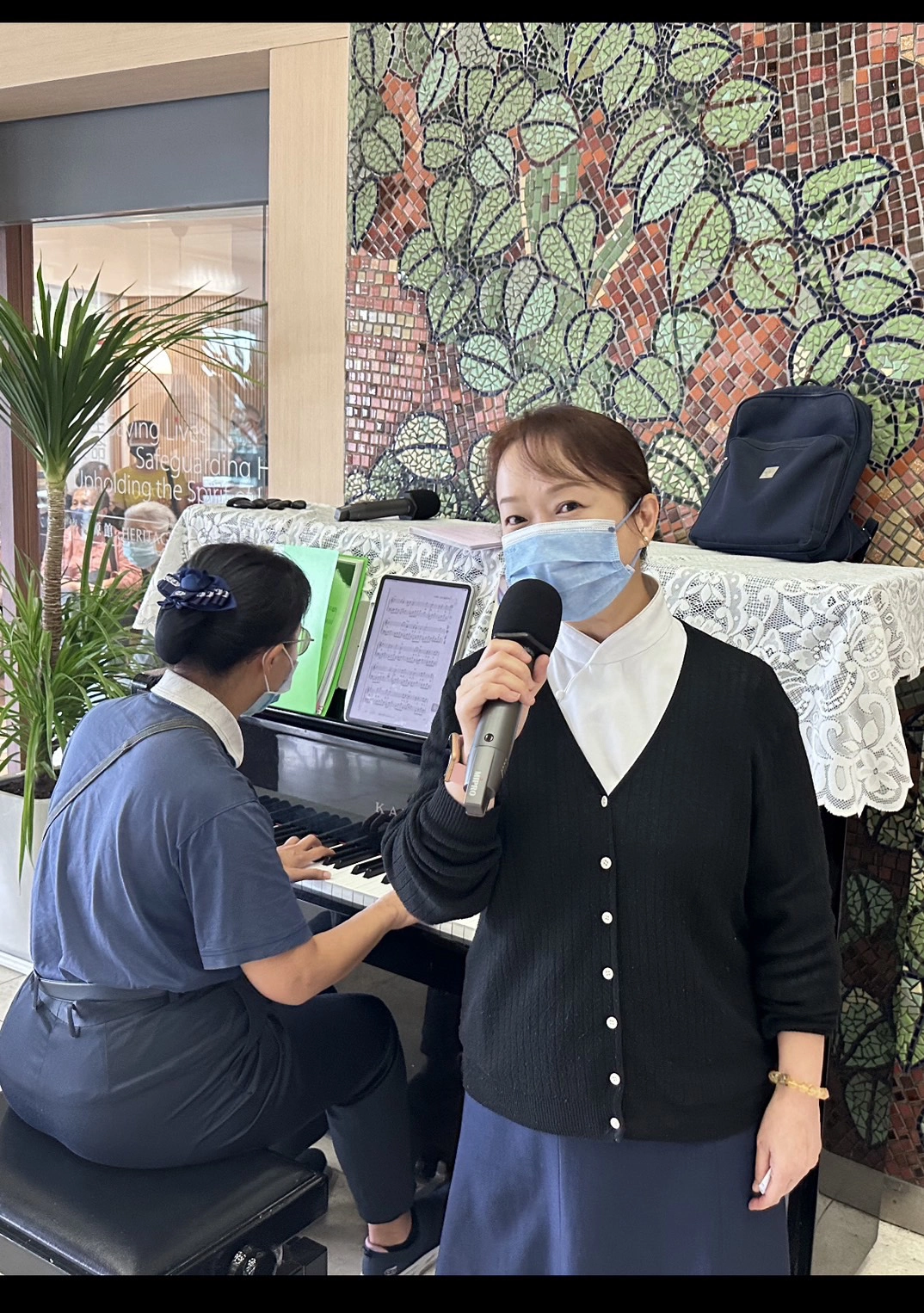 志工陳蓉珍(左,彈鋼琴者)、黃靖惠在大廳分別彈奏、演唱「月亮代表我的心」,吸引許多病友、家屬隨旋律一起唱和。