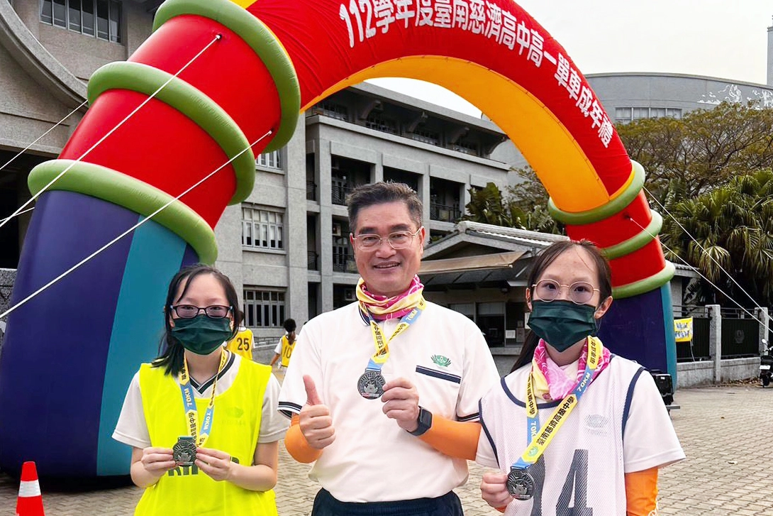 校長與劉家姊妹合影:妹妹千綺作為高一完賽同學,姊姊璧甄擔任高三志工,共同完成賽事。