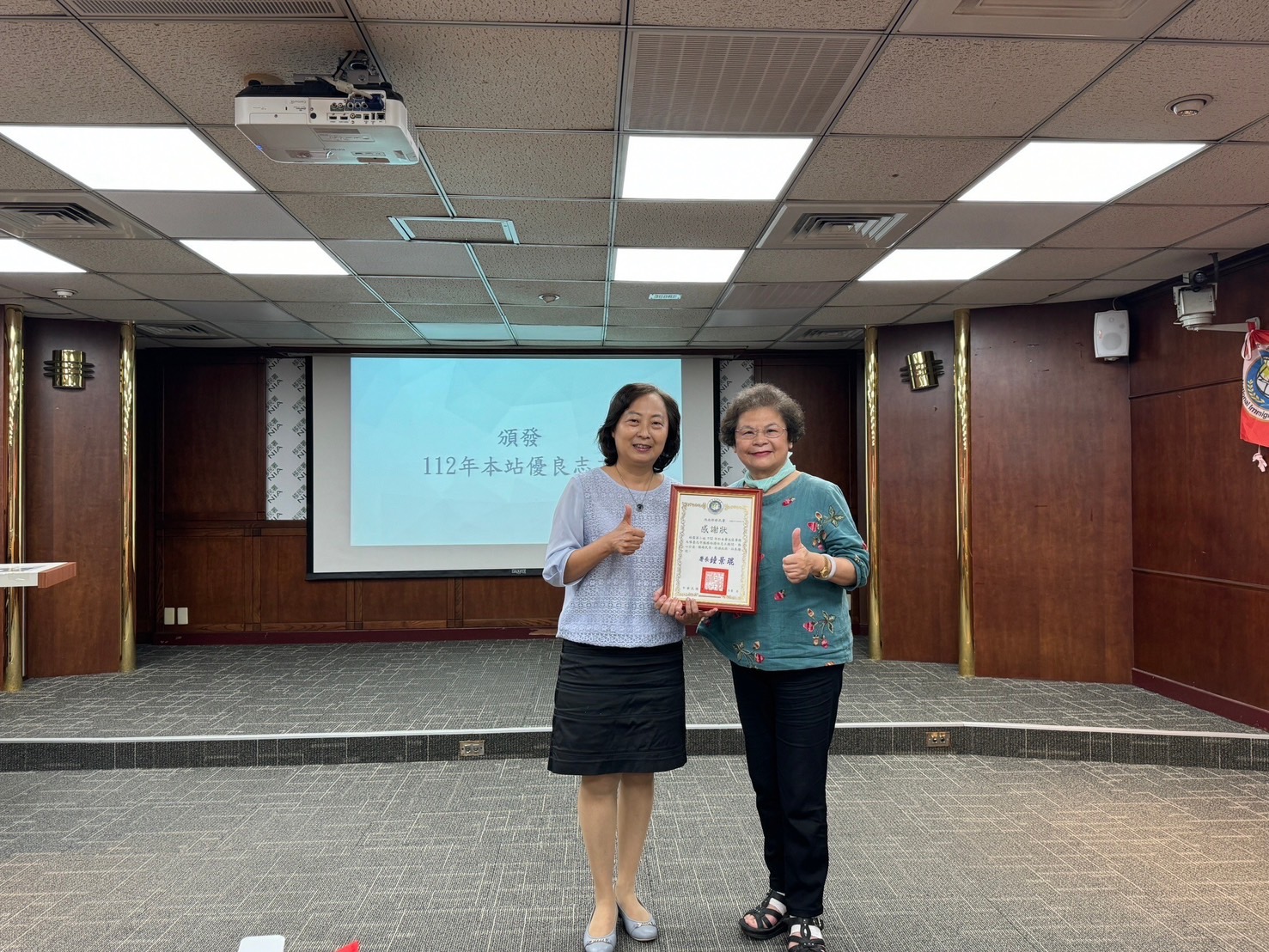 移民署臺北市服務站主任蘇慧雯(左)頒發優良志工獎狀予林雪英(右),服務精神為志工團典範。