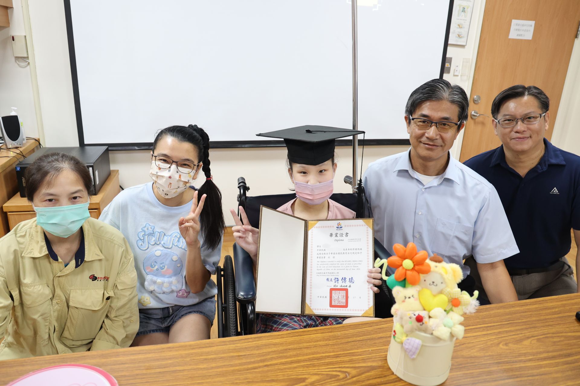 明義國小校長許傳德頒發畢業證書祝賀黃小妹從學校畢業,也從病房畢業,學校導師與師長也一起送上祝福。