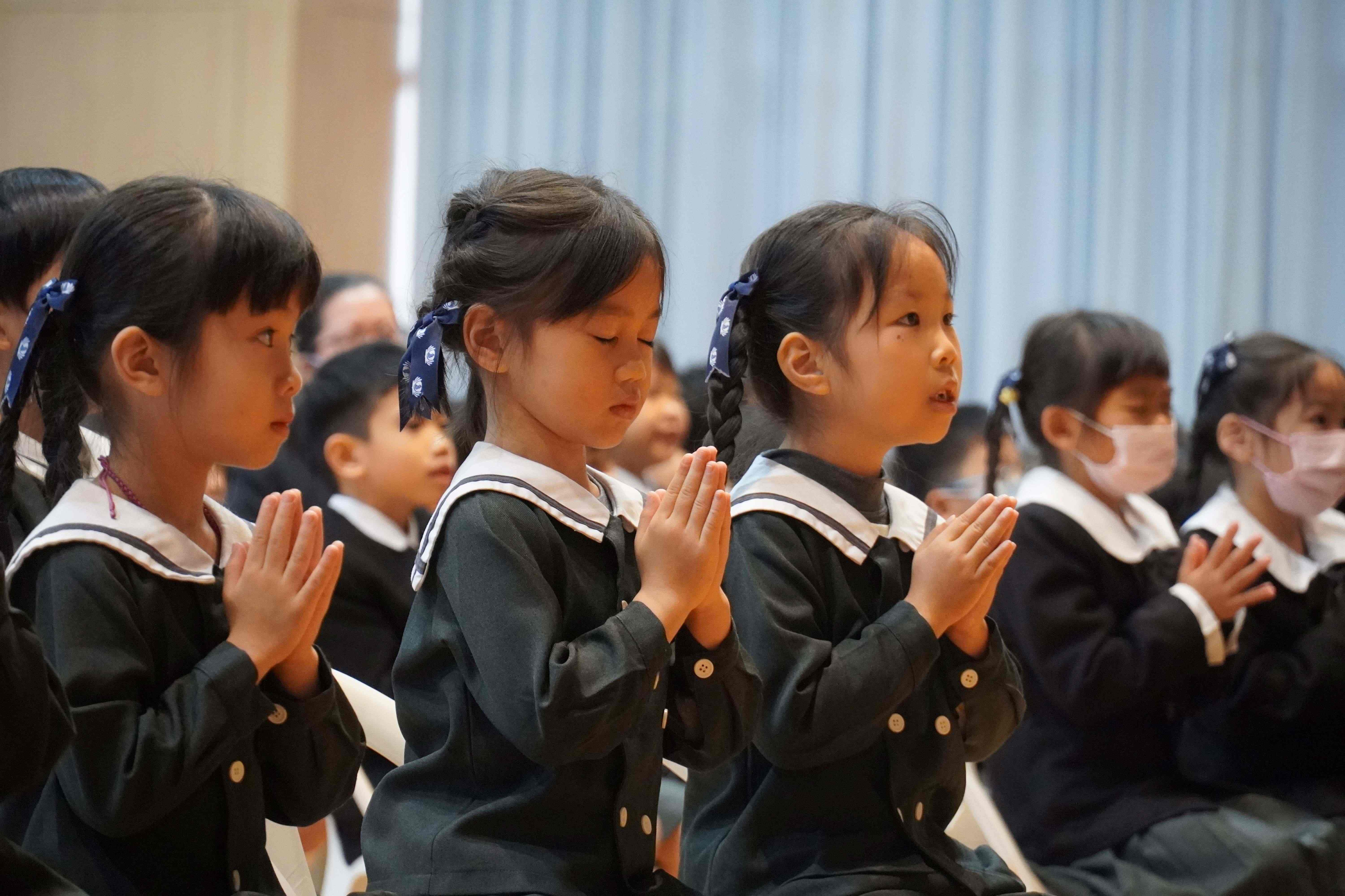 幼兒園孩子坐姿端正,合掌祈禱,誠心祈求天下無災。
