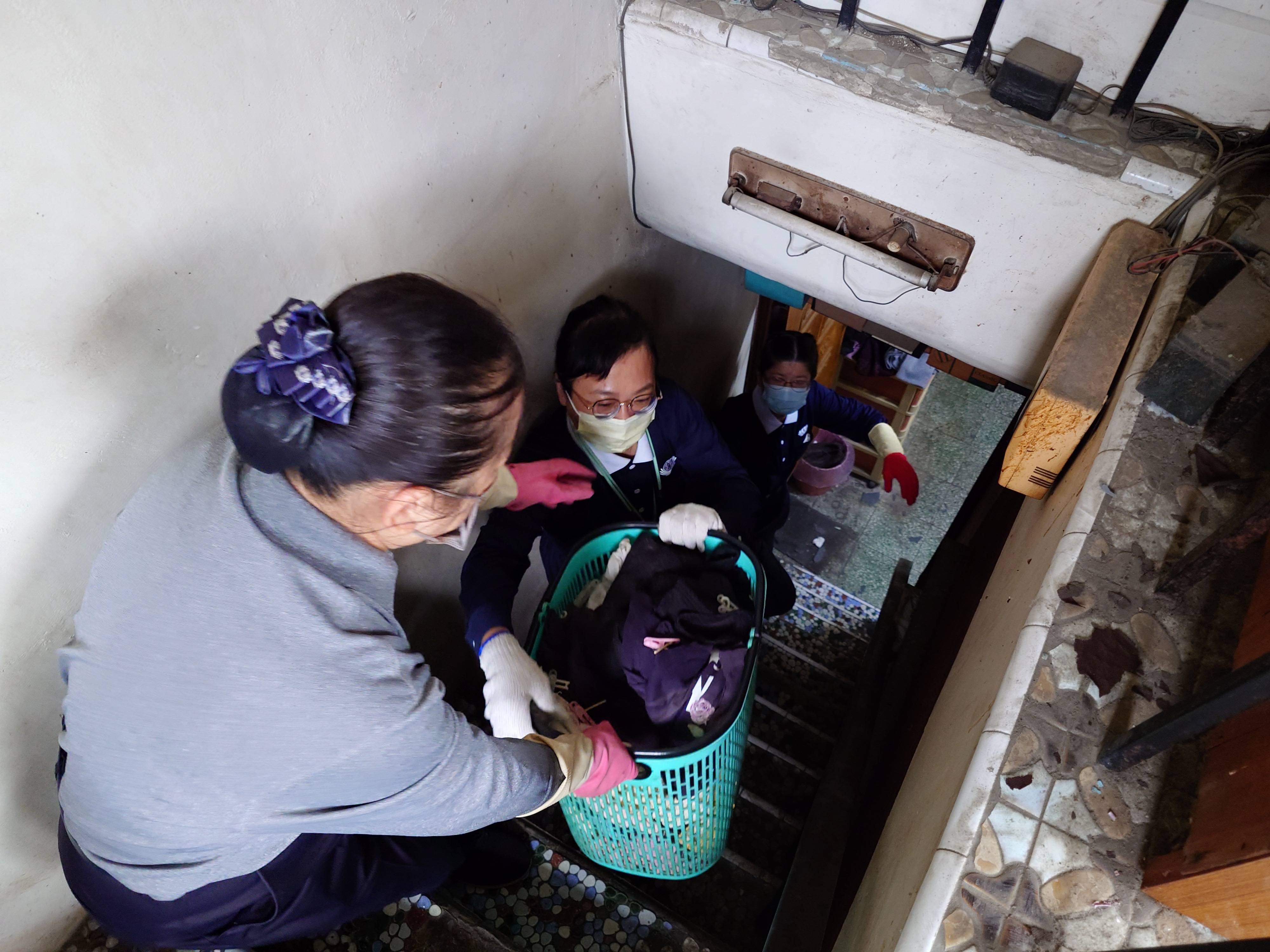 志工以人力接龍將物品從二樓往下傳遞,小心翼翼走在陡峻狹窄的樓梯。