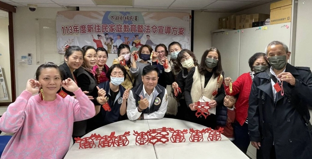 新住民學員十分滿意自己親手做的龍年紅布包及剪春字,開心與移民官合影。