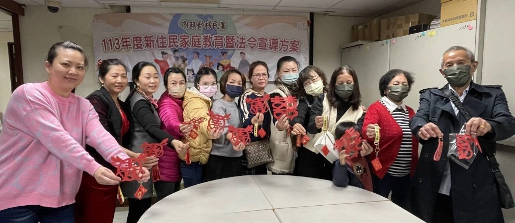 新住民學員手持自己親手做的龍年紅布包及剪春字,開心與講師合影。