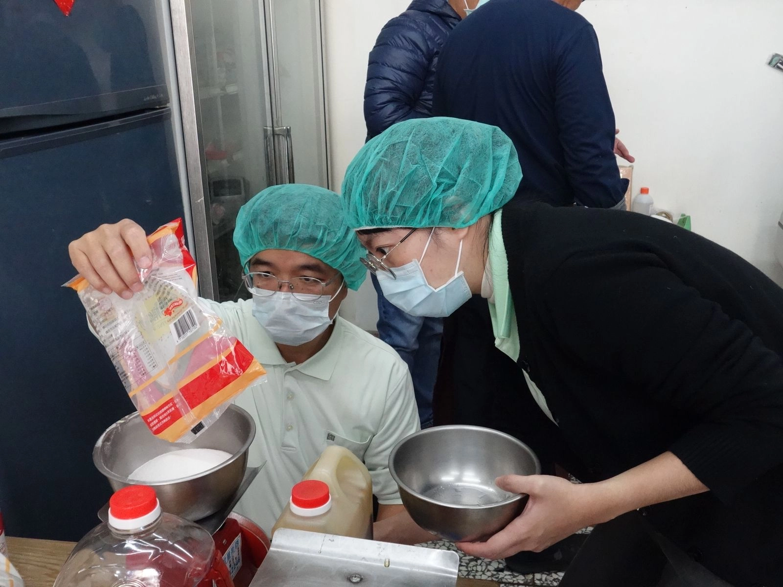斗六慈濟醫院院長室高級專員陳鈞博(左)與同仁專心幫材料秤重