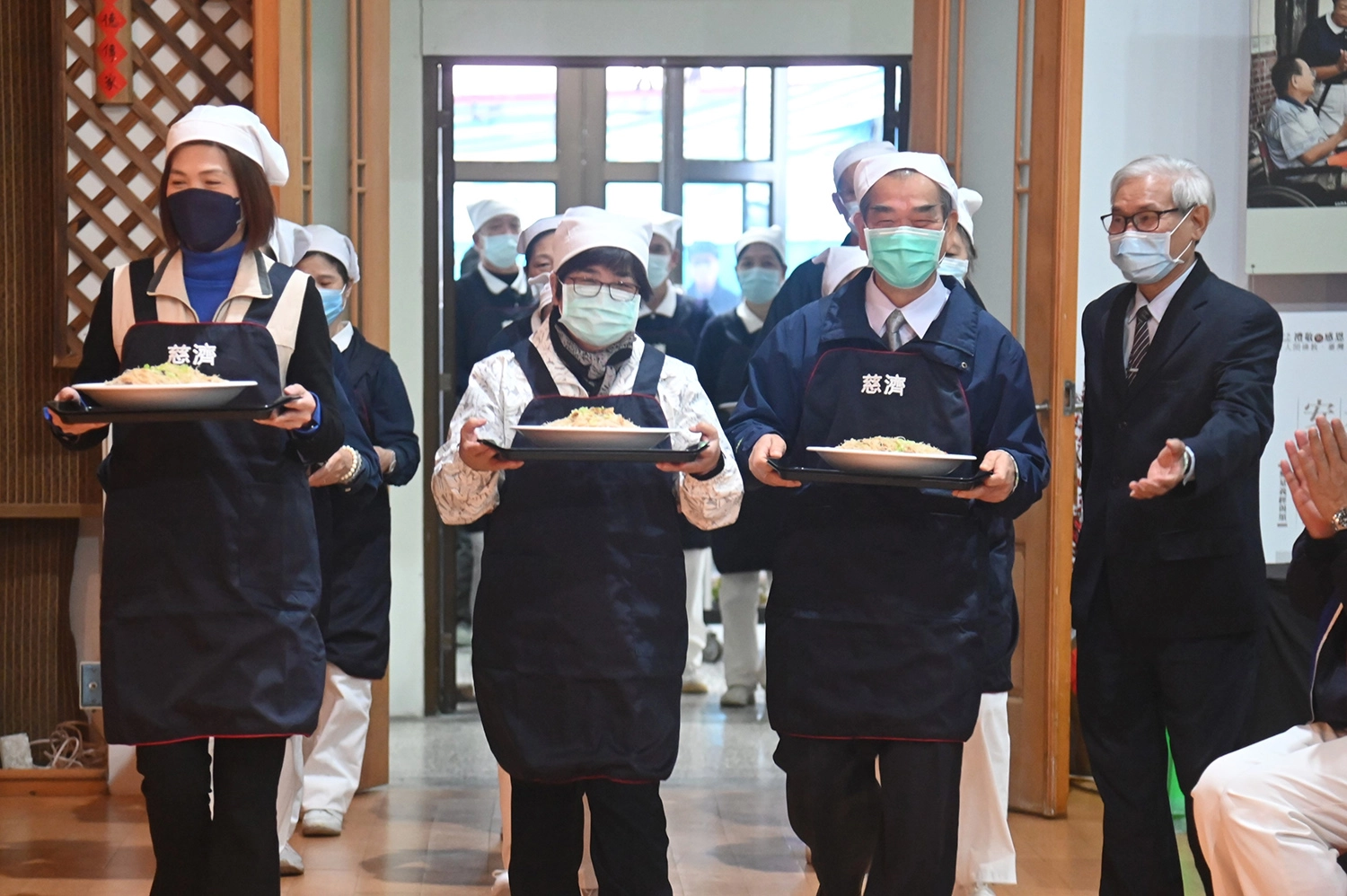 宜蘭慈濟1月21日在羅東聯絡處舉辦冬令發放圍爐,羅東鎮長吳秋齡(左二)、五結鄉長沈徳茂(右二)出席祝福並協助上菜。(圖為慈濟基金會提供)