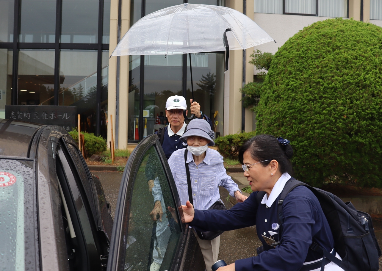 志賀町文化館的發放現場14日午後下起傾盆大雨，顏執行長為行動不便的長者撐傘，用誠懇的情感貼近日本鄉親的。