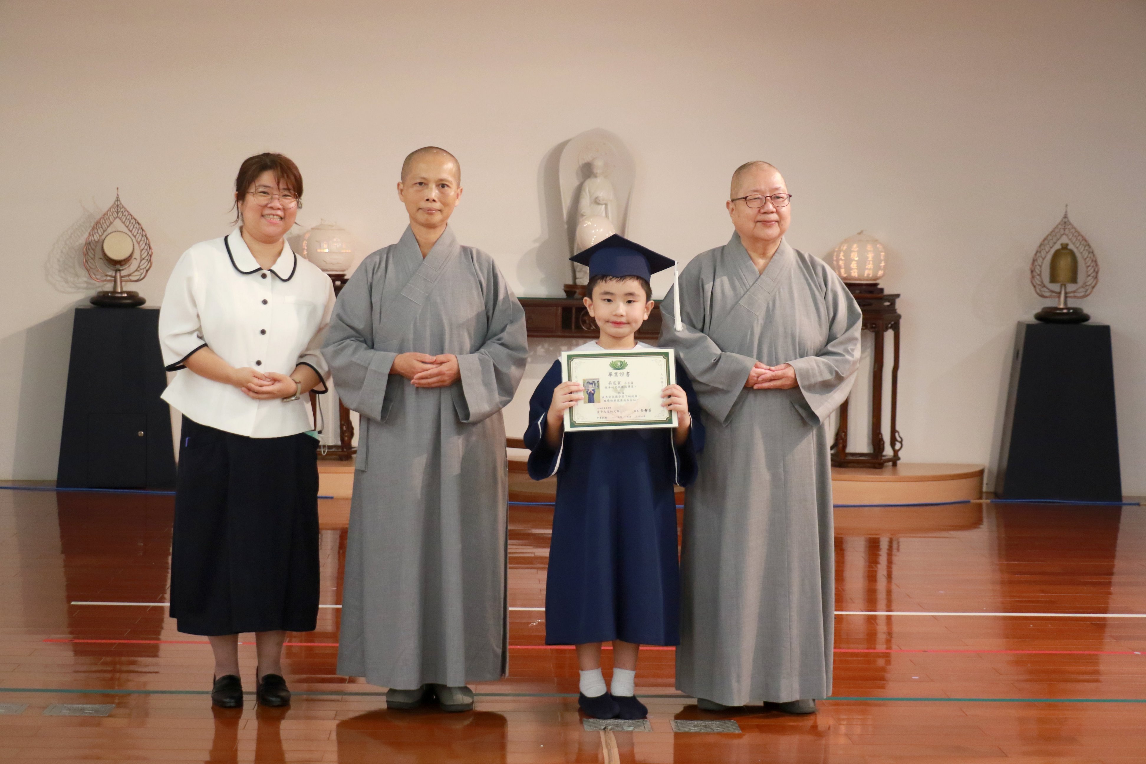 靜思精舍德旭師父（右一）、德守師父（左二）、李靜芳園長（左一）為唯一畢業生吳宸賓送上祝福。
