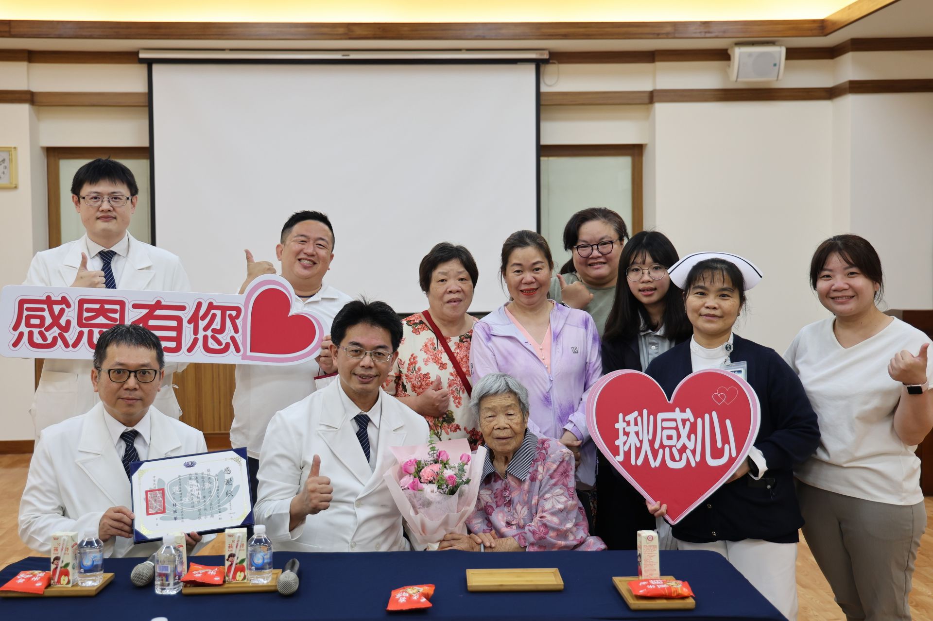 花蓮慈院中醫部何宗融副院長(前排左二)、副主任王健豪(前排左醫)、中醫預防醫學中心副主任陳中奎(後排左一)、中醫病房護理長張素雯(右二)等人代表感恩,並致贈感謝狀,以及花束、淨斯結緣品祝福簡江秀吟(前排左三)「母親節快樂。」