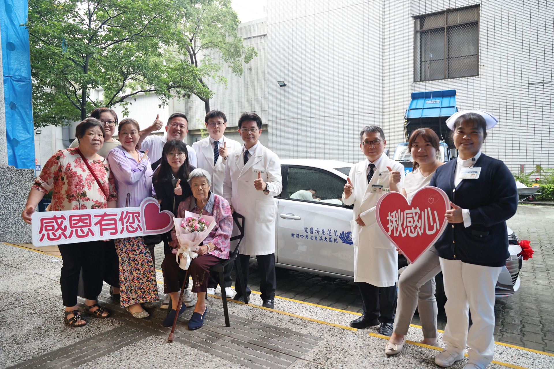 花蓮慈濟醫院何宗融副院長(左八)帶領中醫部代表,與大愛捐車簡江秀吟女士(坐者)一家人,在新車前合照。
