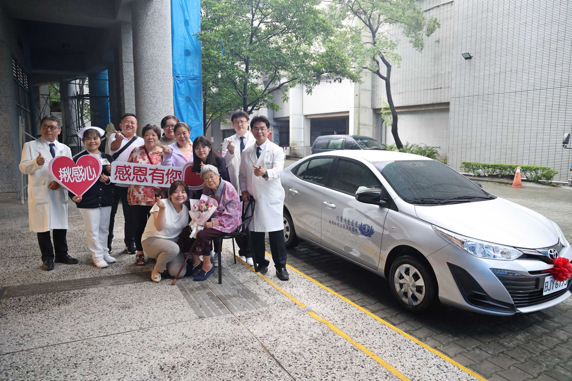 花蓮慈濟醫院何宗融副院長(右一)帶領中醫部代表,與大愛捐車簡江秀吟女士(坐者)一家人,在新車前合照。