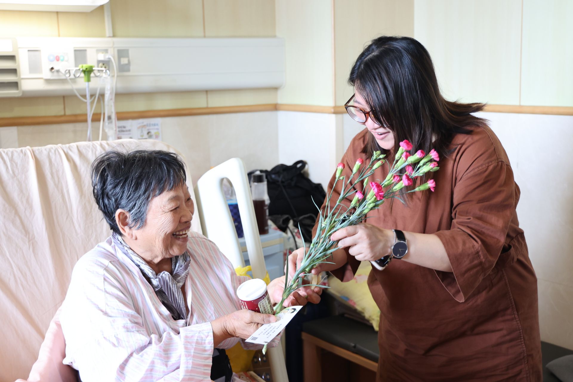 陪病的張女士將康乃馨送給住院中的媽媽,希望帶給媽媽雙倍的祝福,祝福她早日康復。