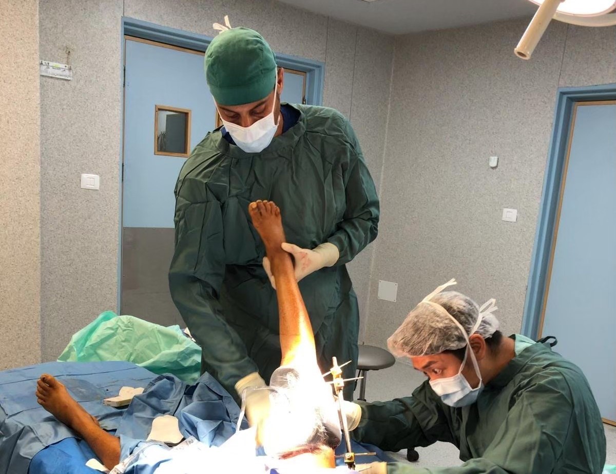 鄔逸群醫生在加薩南部納瑟醫院為一位下半身和腿部受傷的十歲男孩進行清創。照片攝於2024年7月。
