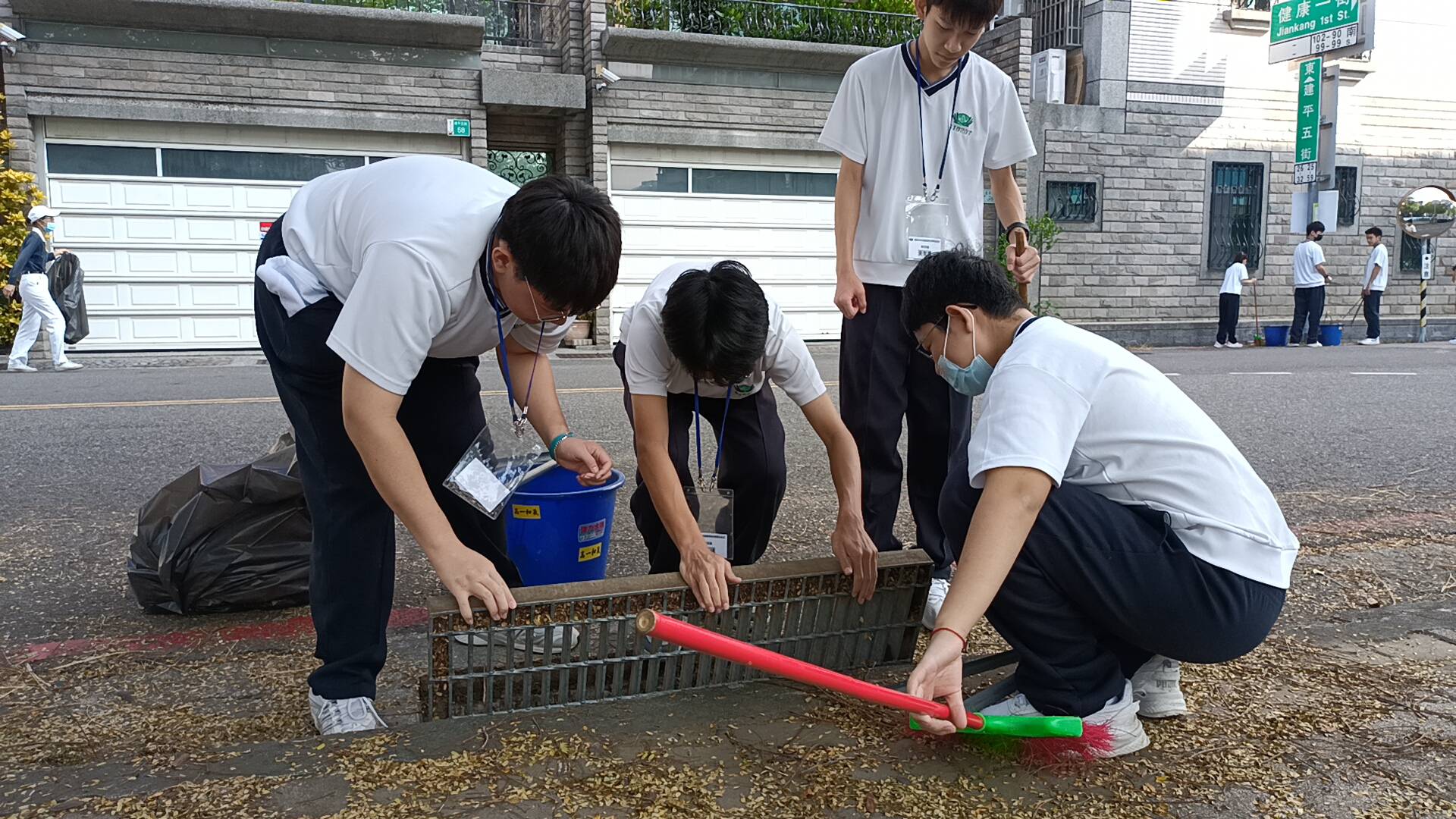 學生們同心協力搬開水溝蓋進行清掃。
