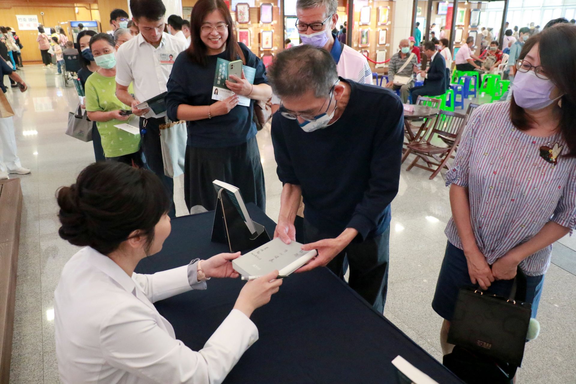 《中西合療,抗癌逆轉勝》新書發表會上,莊佳穎醫師(左)為購書讀者簽名。