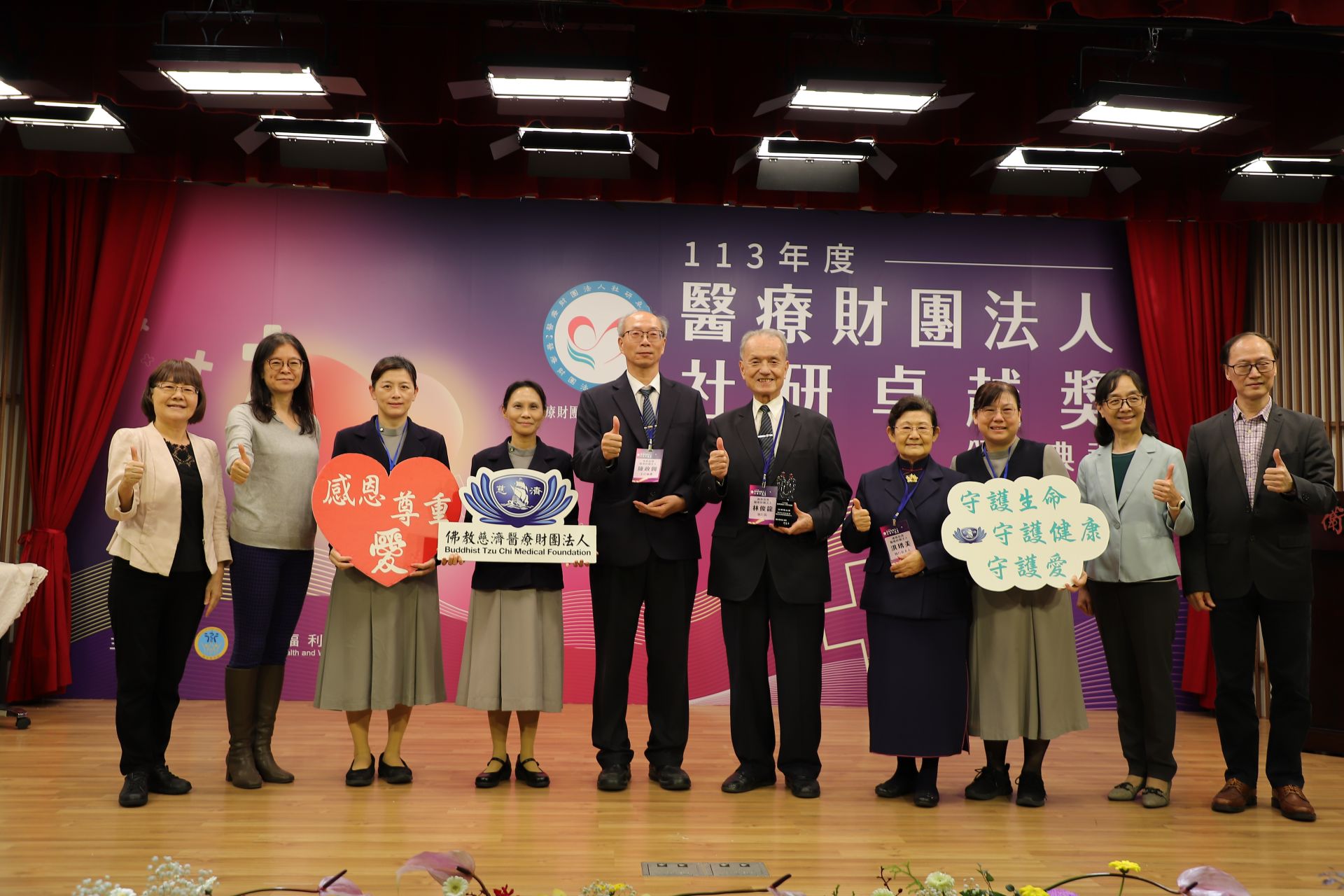衛福部主管、評審委員與獲獎單位慈濟醫療法人團隊合照。左起:評審委員王秀紅考試委員、衛福部醫事司劉玉菁副司長、慈濟醫療法人醫務管理室蔡淑芬高專、藍寅萱主任、執行長辦公室陳政興主祕、林俊龍執行長與夫人洪琇美女士、李淑娟組長、國立政治大學何怡澄教授、國立臺北大學郭振雄教授。