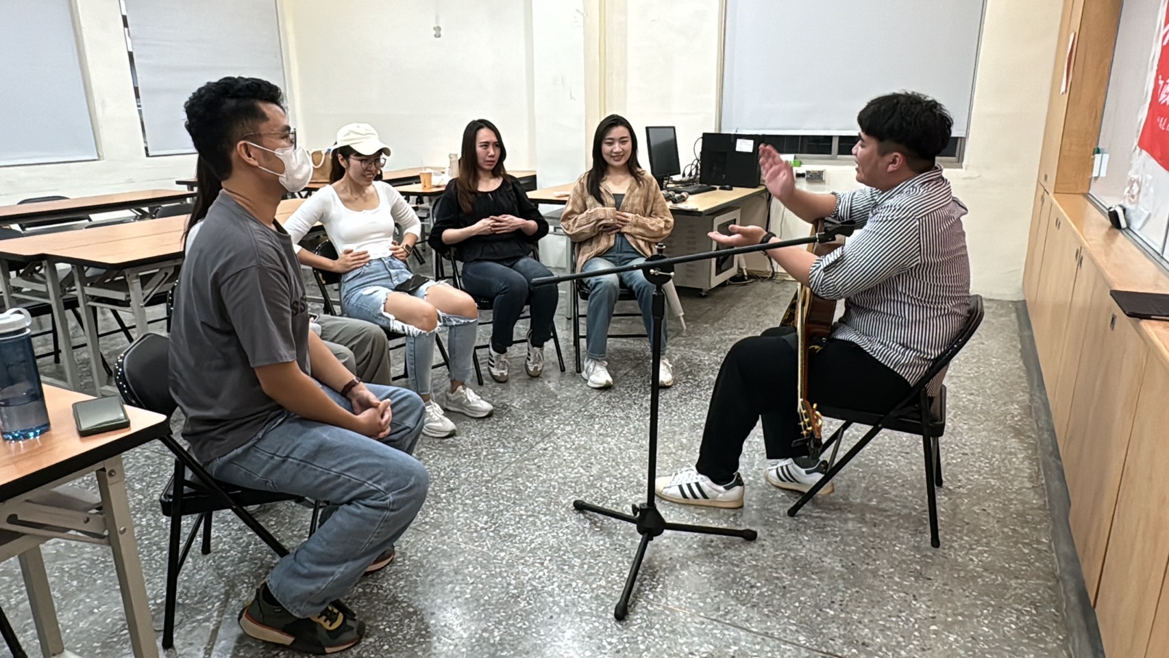 擔任講師的阿美族樂團主講吳政諺(左)指導移民署新住民二代親善大使曾心怡(右)唱歌時的咬字小技巧。