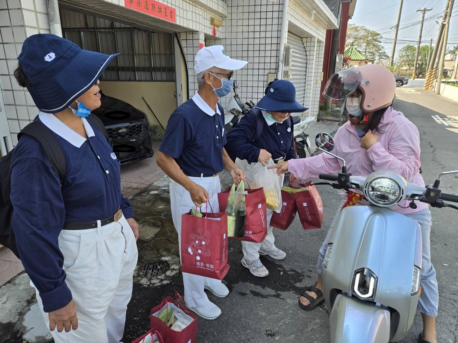 女機車騎士騎機車路過看到路邊提著安心祝福禮的慈濟人,立即送上一袋香蕉要給慈濟志工享用,感恩慈濟人前幾天來發熱食便當