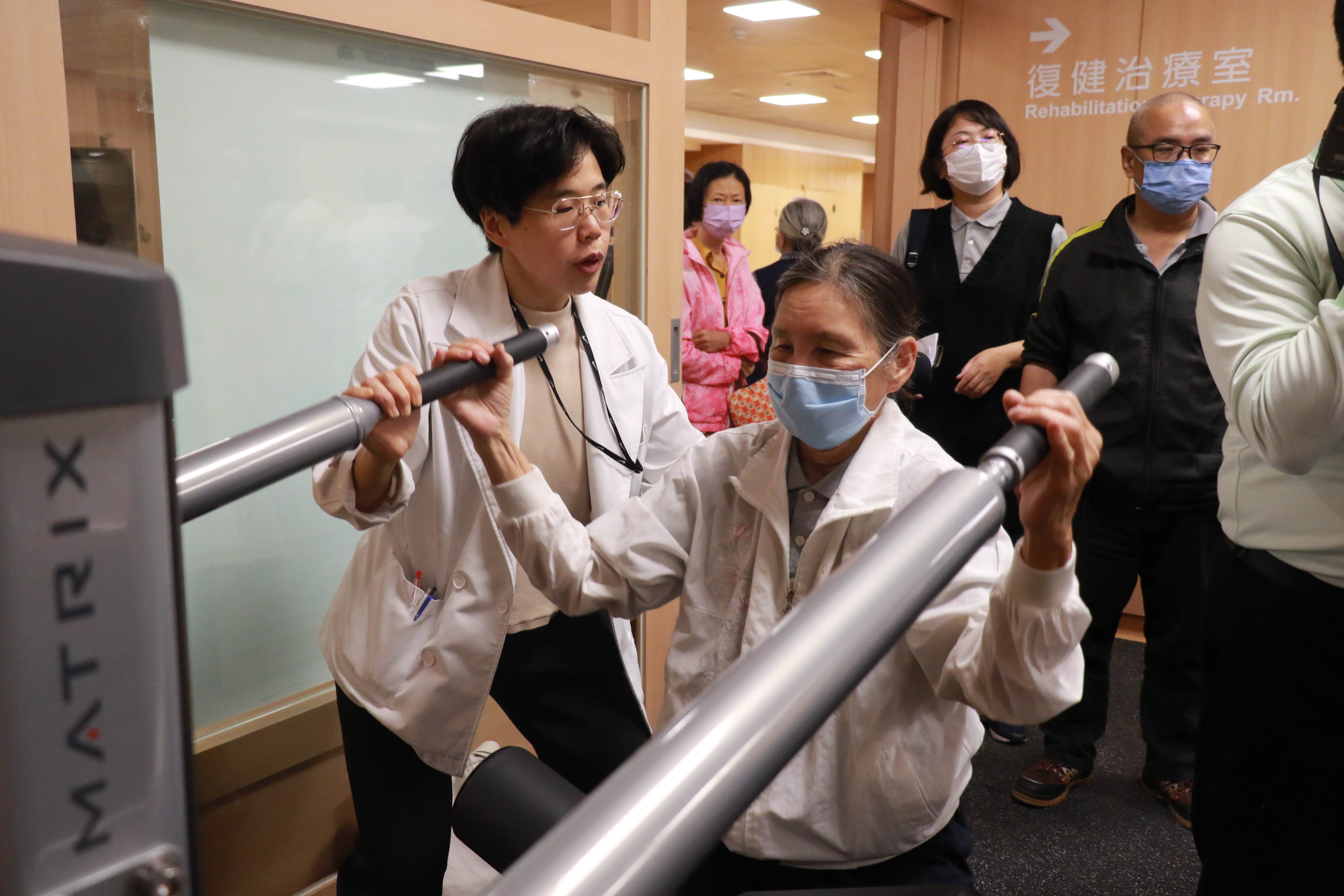 訓練中心負責人陳佳菁醫師(左一)指導社區長輩操作負重設施。