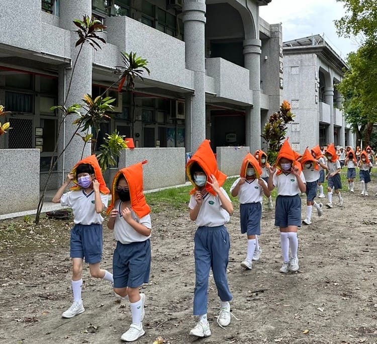地震稍歇,小學部學生戴上頭防災頭套,遠離建築物,進行避難疏散動作。