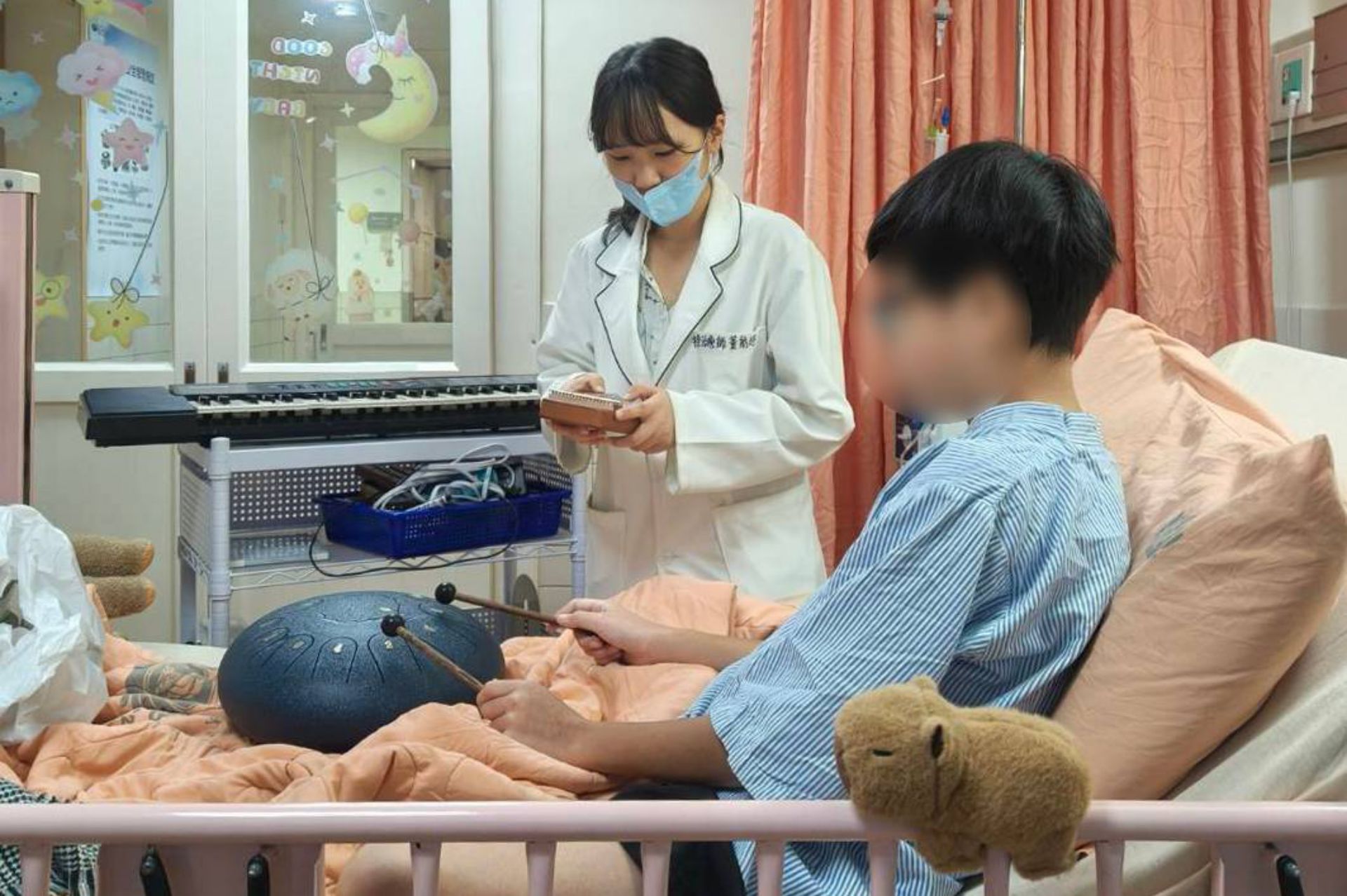 藝術治療師與音樂治療師到病房,藉由音樂與手作遊戲,減輕樂樂住院不安的情緒。