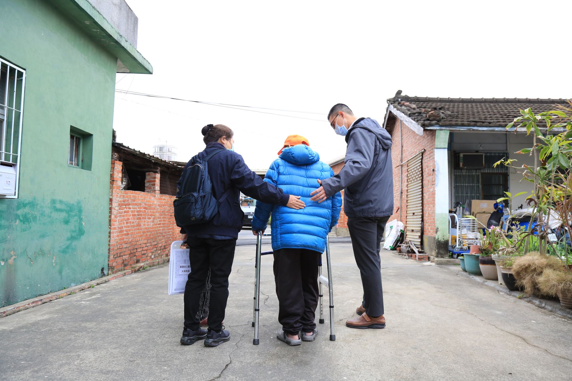 人醫會簡振宇醫師及郭惠子藥師陪伴長者以助行器行走，並隨時注意其安全。