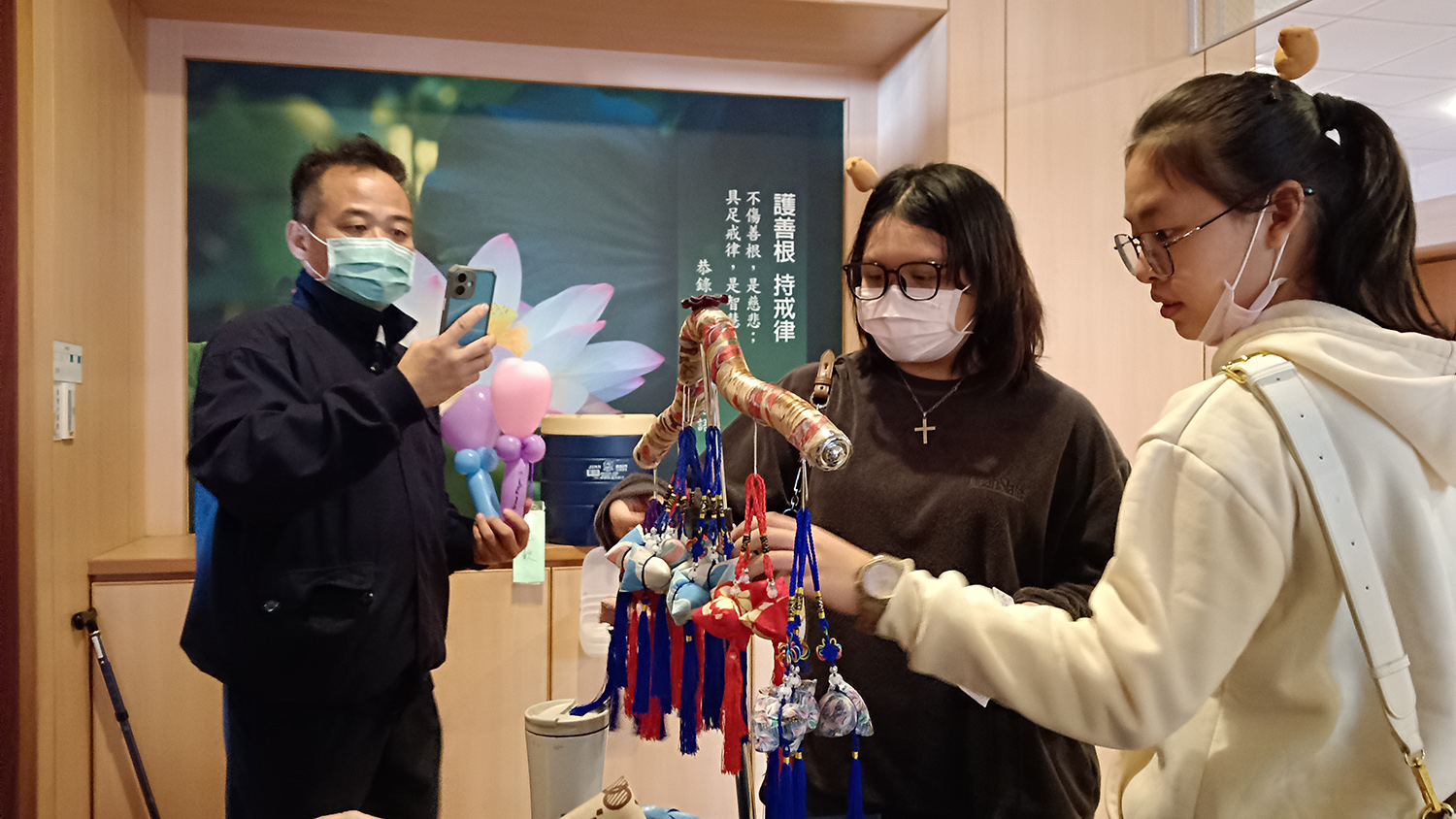 慈濟志工張海清(左),本身也有擔任寄住家庭的「Home爸」,期間剛好有兩位來自馬來西亞的短期遊學高中生在他家寄住,就邀約她們一起來參加慈濟歲末祝福感恩會。