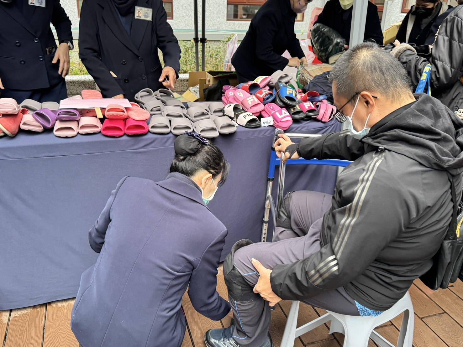 志工彎下腰幫忙行動不便的服務家庭試穿及挑選新鞋。