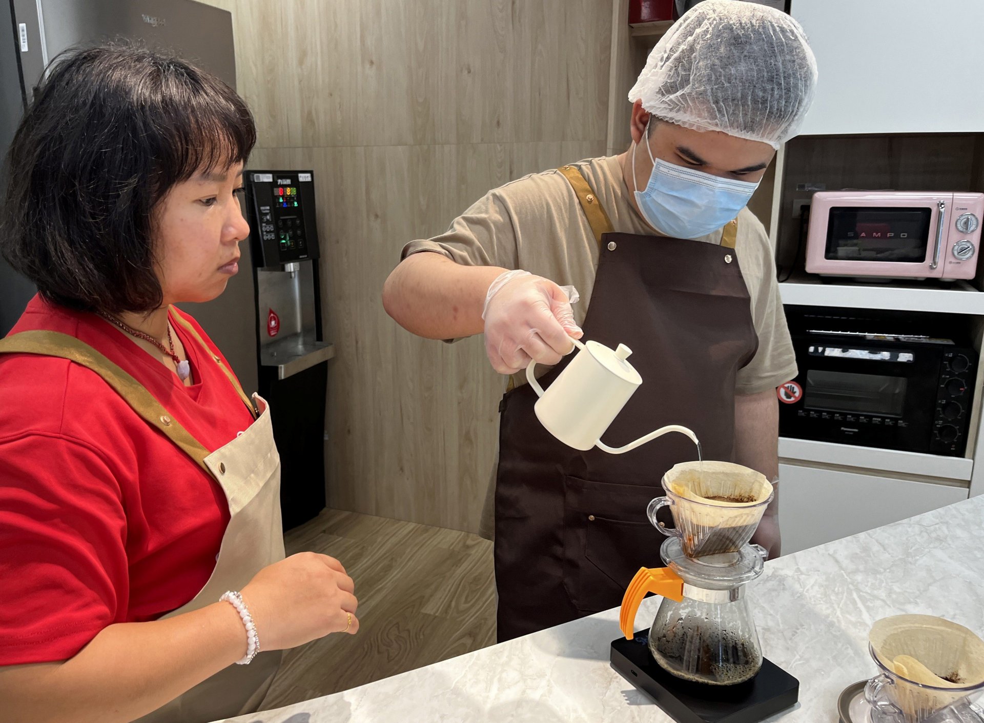 小育(右)在伊甸教保員莊嫚婷(左)的指導與陪伴下,逐漸熟悉手沖咖啡的技巧。