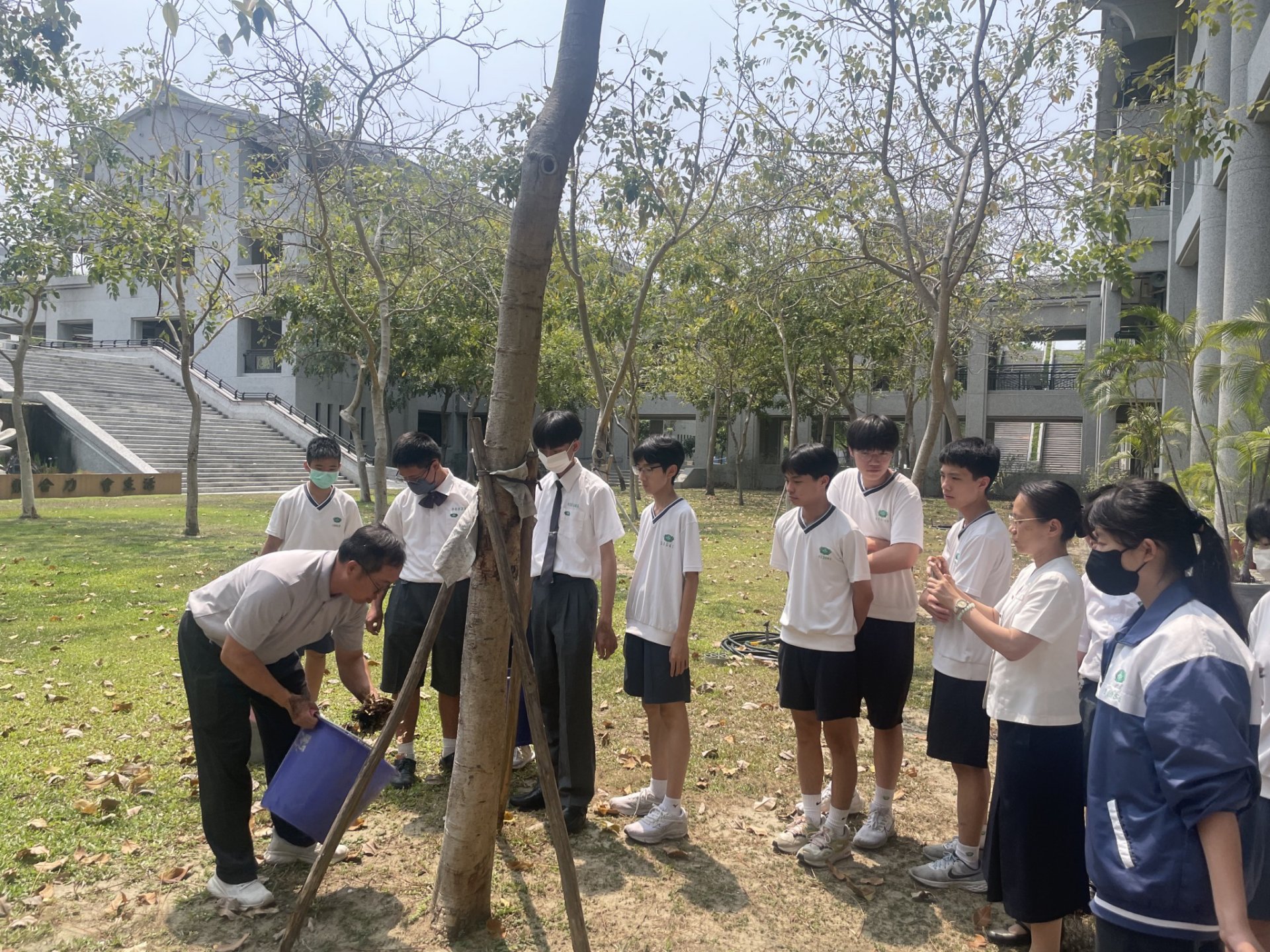 總務處同仁向校內師生示範落葉堆肥使用方式,推動環境永續。