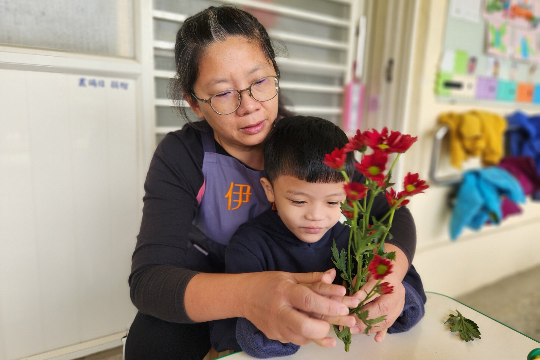 老師帶著幼童阿中,練習將花枝修剪