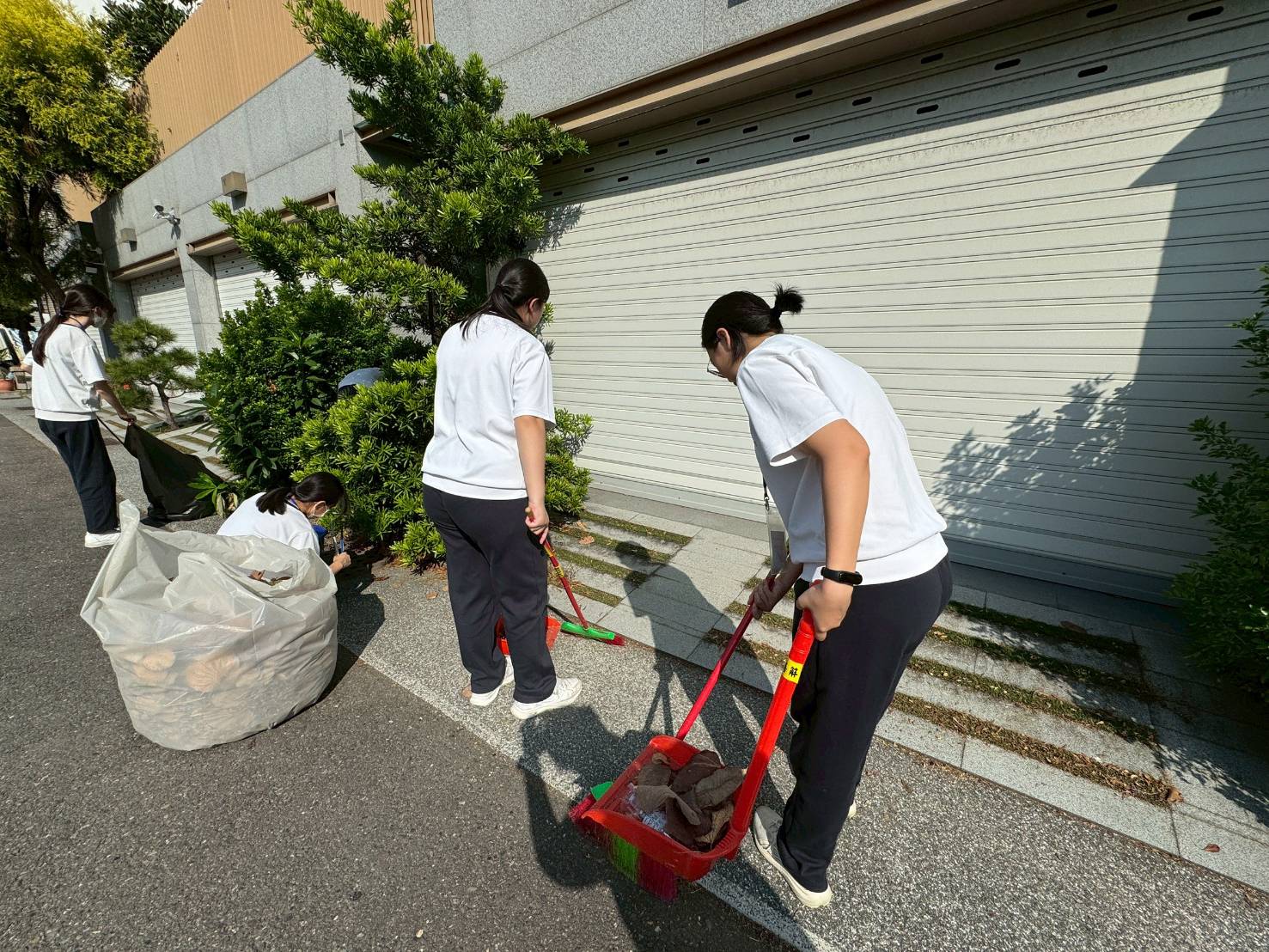 學生走入鄰里,協助清掃住家門前落葉。