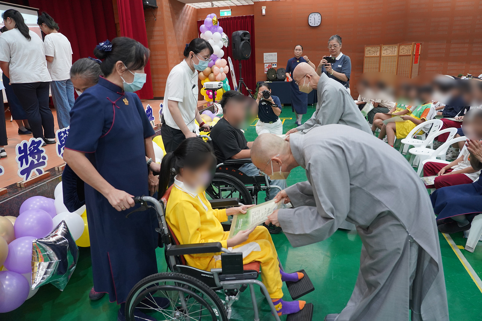  精舍師父為行動不便的新芽孩子頒發今年得獎獎狀，展現慈悲關懷與肯定，鼓勵孩子在愛與祝福中繼續前行。