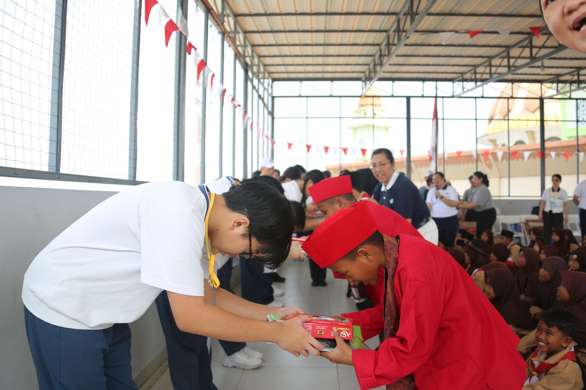 慈中學生在卡馬爾.穆阿拉村旁的努魯伊斯蘭小學,恭敬地將文具與生活用品送給孩子。