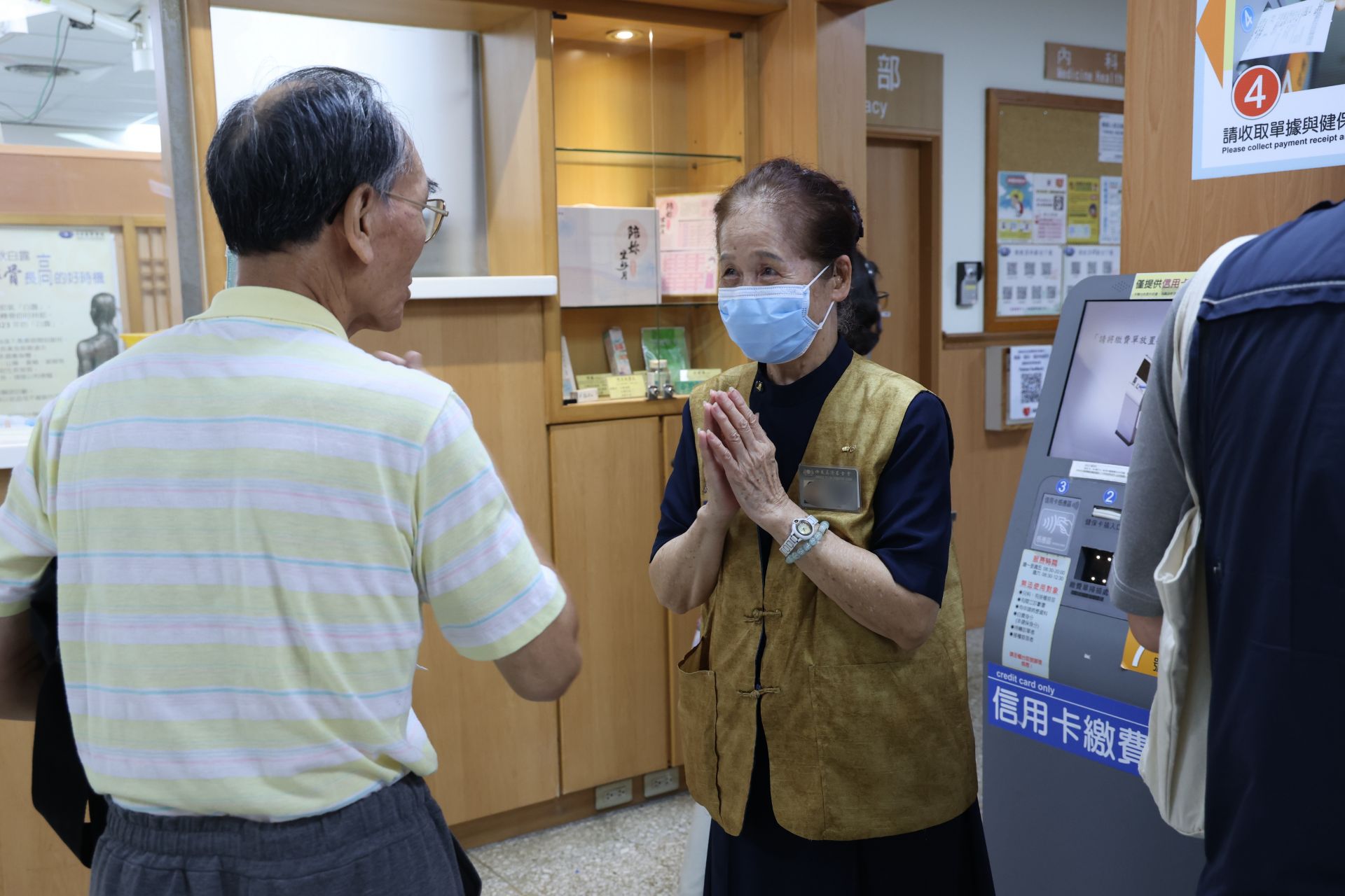 服務時數18,412小時的詹玉(右)38年來持續投入醫療志工服務。81歲的她至今仍常在大廳的繳費機、掛號機及批價抽號機旁協助民眾。